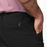 A close-up of the back pocket area of the black pants, highlighting the subtle embroidered logo near the pocket.