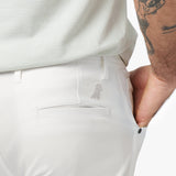 A close-up of the back pocket area of the white pants, highlighting the subtle embroidered logo near the pocket.