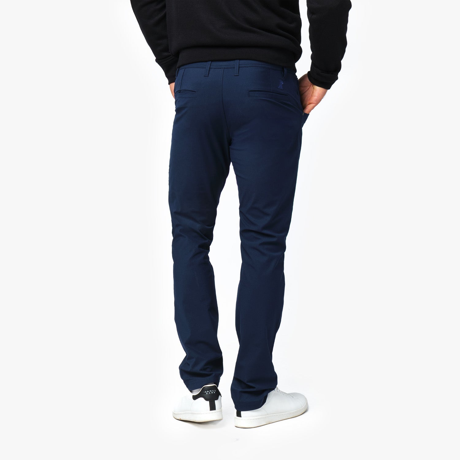 A side view of the man wearing navy blue pants and white sneakers, showing the fit along the leg.