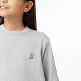 Side view of the child wearing the gray sweatshirt, focusing on the chest area and embroidered dog logo.