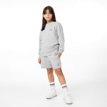 Full-body view of a child wearing the gray sweatshirt paired with matching jogger shorts and white sneakers, styled casually