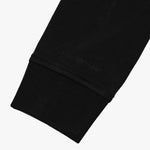 Close-up of the cuff detail on the black sweatshirt, emphasizing the stitching and fabric texture