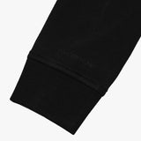 Close-up of the cuff detail on the black sweatshirt, emphasizing the stitching and fabric texture