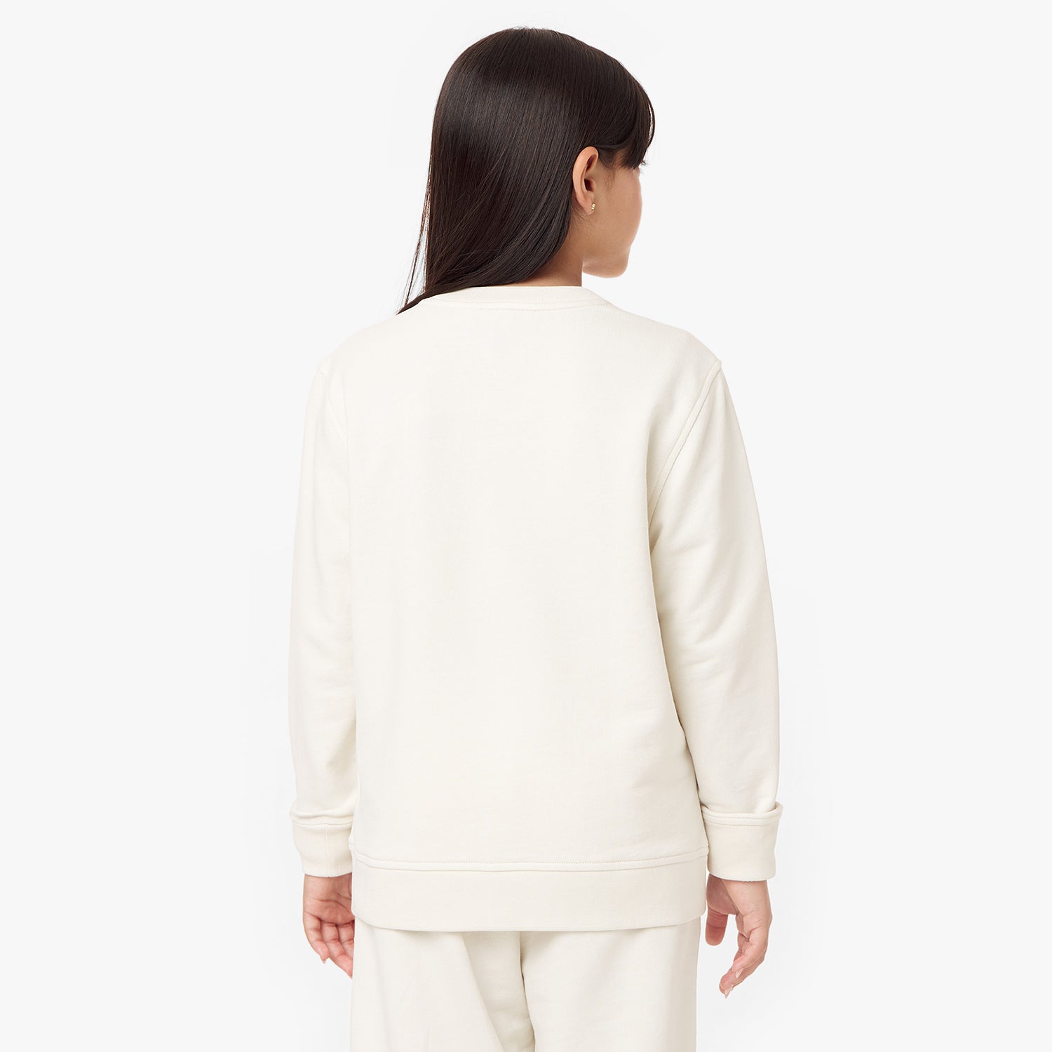 Back view of a child wearing the cream-colored sweatshirt, showcasing its clean and simple design