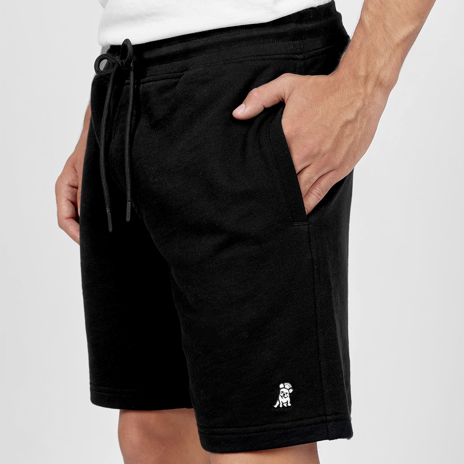 This image shows a close-up of the black athletic shorts with the embroidered logo on the bottom left side. The drawstring waistband adds a touch of functionality, allowing for an adjustable fit, while the soft fabric suggests comfort and breathability.