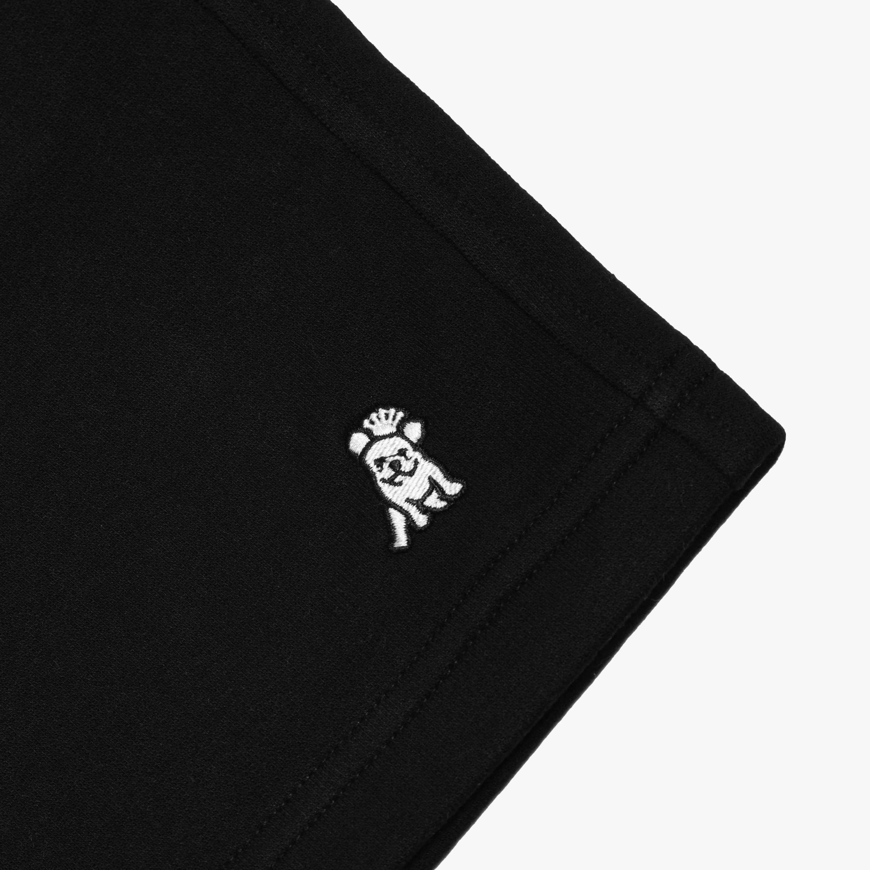 Close-up of the embroidered dog logo on the black shorts, highlighting the detailed stitching