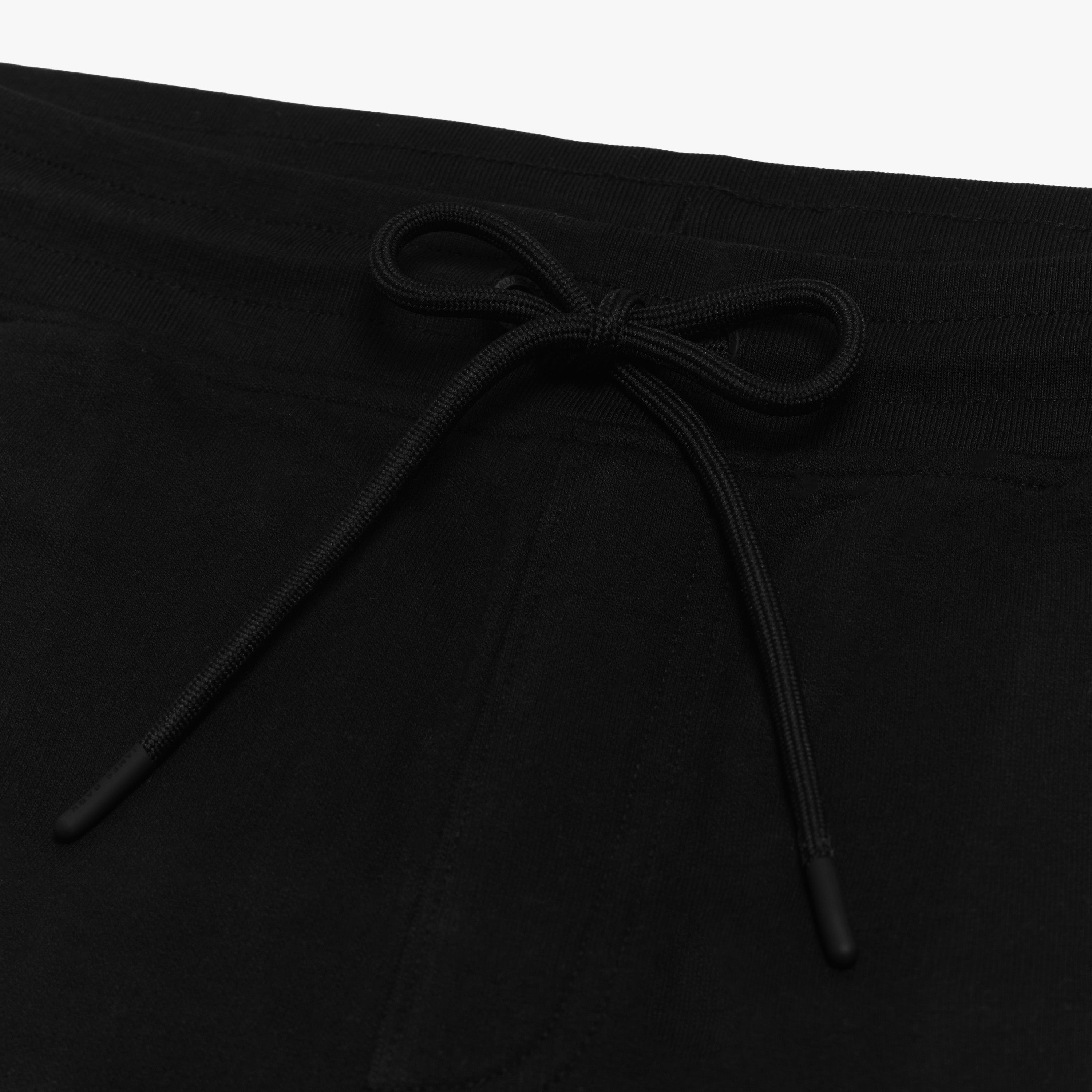 Close-up of the drawstring waistband on the black shorts, emphasizing the adjustable fit and fabric texture