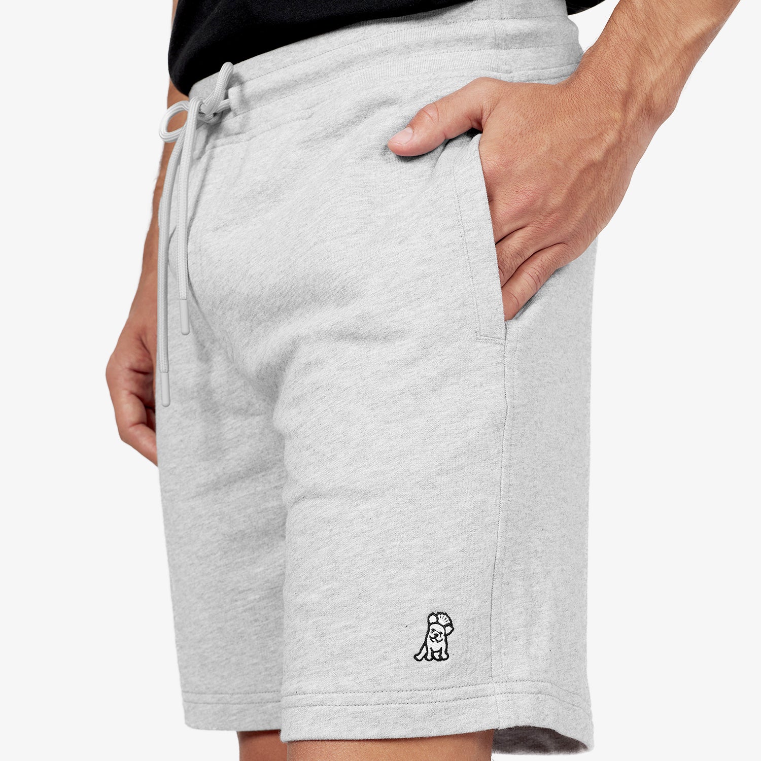 This close-up showcases the side profile of the gray athletic shorts. The design features a functional side pocket, perfect for convenience, and an embroidered logo detail near the hem, adding a subtle touch of branding. The drawstring waistband ensures an adjustable and secure fit, making these shorts ideal for both leisure and activity.