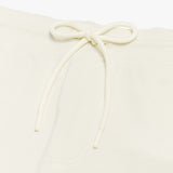 Close-up of the drawstring waistband on the cream-colored shorts, emphasizing the adjustable fit and fabric texture