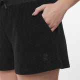 Close-up of a model's hand resting in the pocket of black shorts, highlighting the texture, pocket design, and a subtle embroidered dog logo near the hem