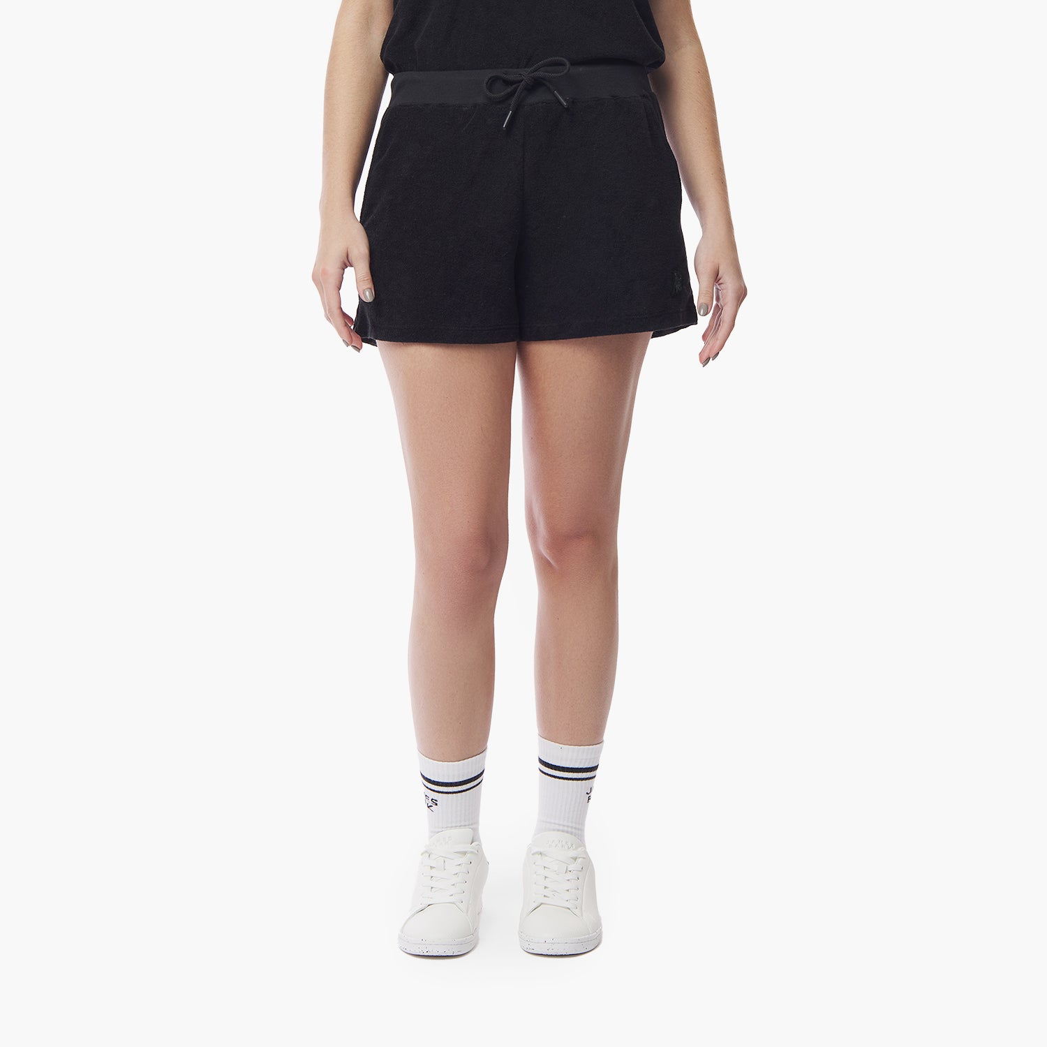 Front view of black shorts worn by a model, paired with white socks and sneakers against a white backgroun