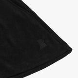 Close-up of the hem of black shorts, featuring a subtle embroidered logo of a dog near the edge, highlighting the fine details and texture of the fabric