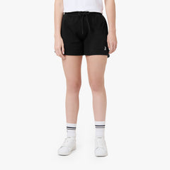 This image features the model wearing black athletic shorts, paired with white sneakers and striped socks. The shorts, like in the previous images, have the small logo on the lower left side. The model is also wearing a white t-shirt. The look is simple yet stylish, maintaining a casual vibe. 