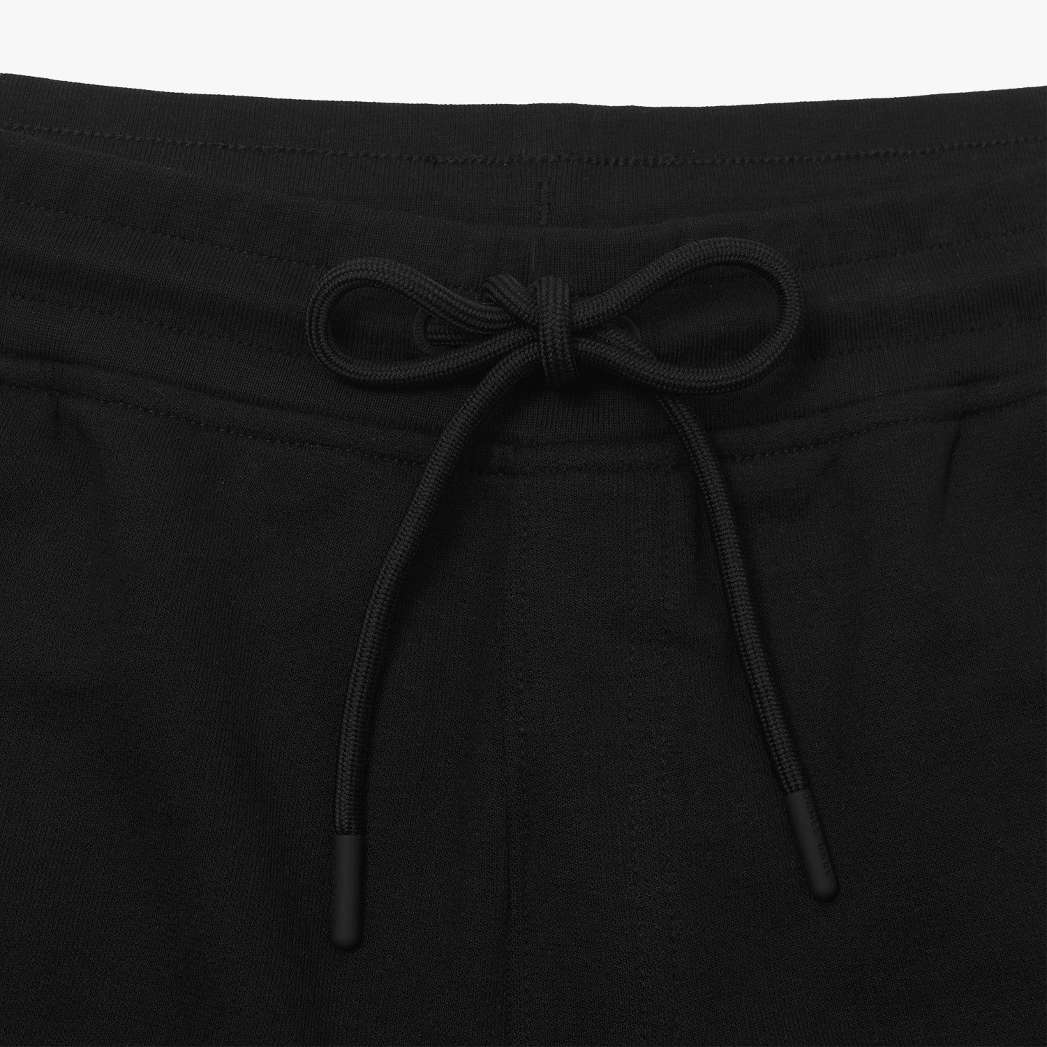 This close-up image shows the waistband of the black shorts, highlighting the drawstring tie. The drawstring is black, matching the color of the shorts, and has tipped ends. This adds to the overall simple and clean aesthetic of the shorts