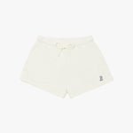 Beige shorts laid flat with an elastic waistband, drawstring, and a small embroidered logo on the lower left side