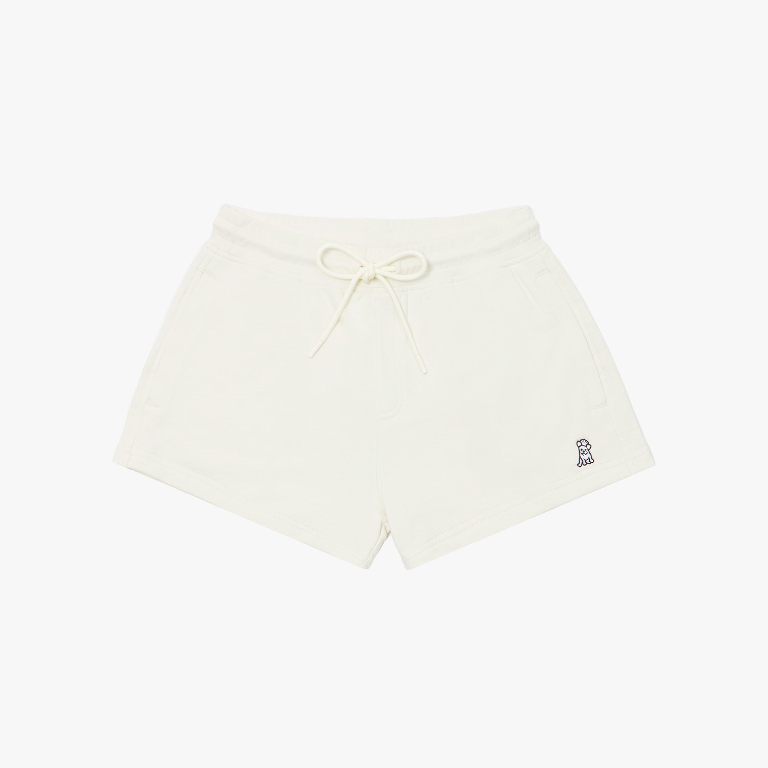 Beige shorts laid flat with an elastic waistband, drawstring, and a small embroidered logo on the lower left side