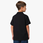 Rear view of the boy wearing the black polo shirt, showing the plain back design.