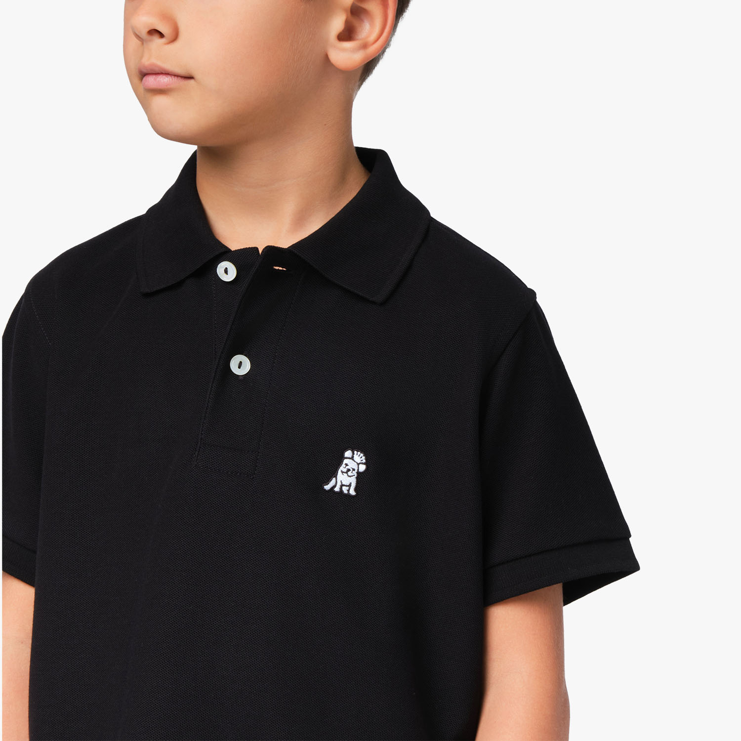 Close-up of the chest area of the black polo shirt, featuring the small embroidered logo.