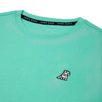 Close-up of the small white embroidered logo on the front of the mint green t-shirt.