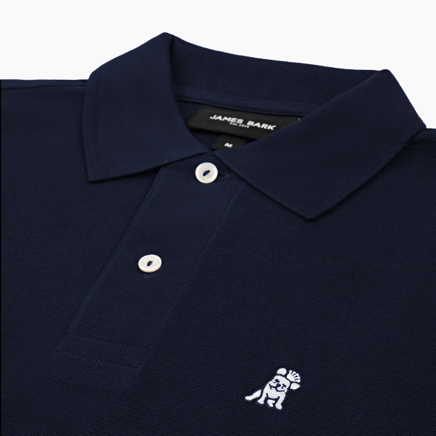 A close-up of the collar and button details of the navy blue long-sleeved polo shirt, showing the inner label.