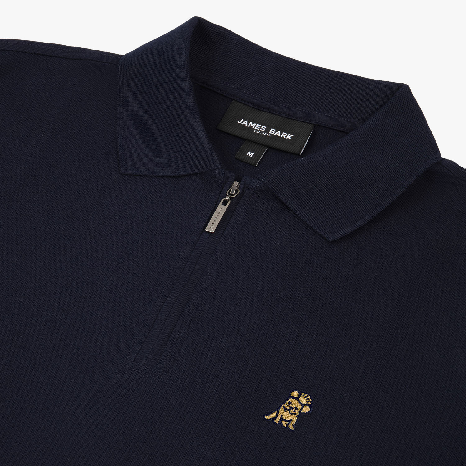 Flat lay of the navy blue polo shirt, with a gold embroidered logo on the left chest