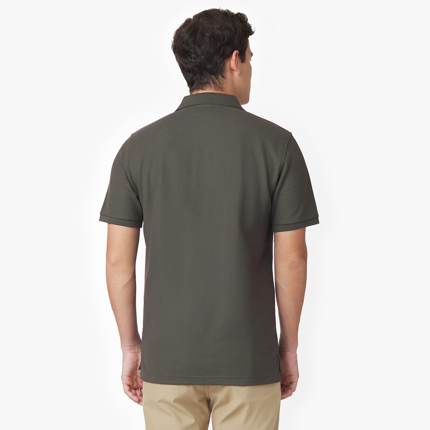 Back view of a male model wearing an olive green polo shirt and tan pants