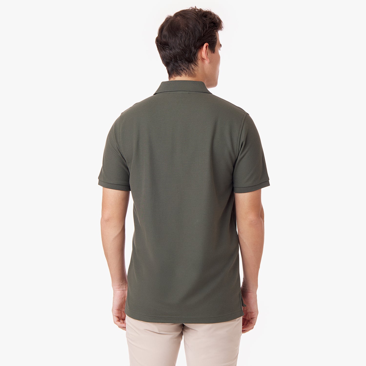 Back view of a male model wearing an olive green polo shirt and tan pants