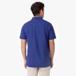 A back view of a man wearing the same royal blue James Bark polo shirt, showing the clean and minimal design from behind