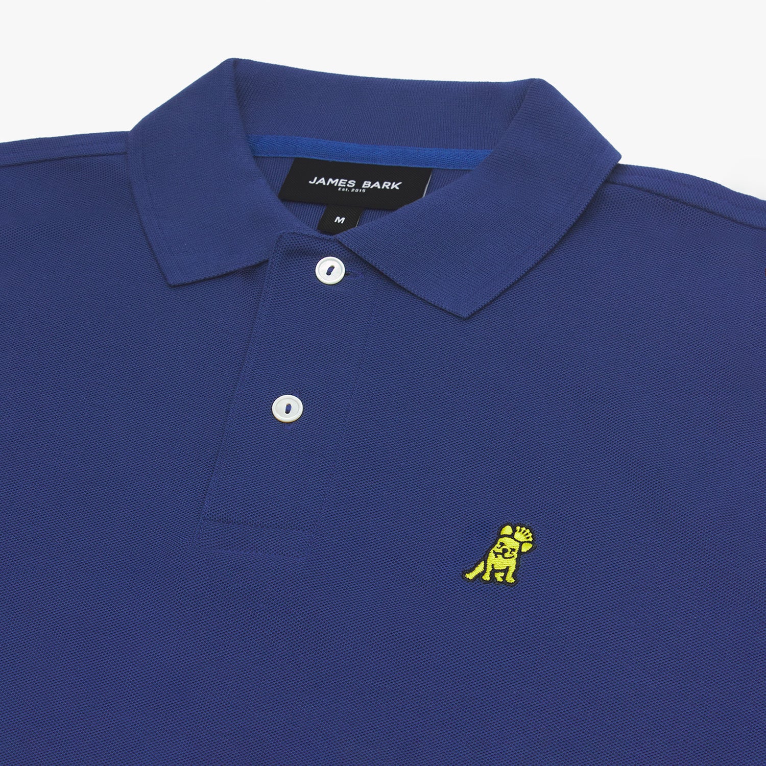 A close-up of the collar and upper chest area of the polo shirt, highlighting the texture of the fabric, white buttons, and the yellow embroidered dog logo