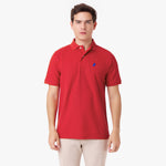 Male model wearing a red polo shirt with a blue embroidered dog logo and tan pants, standing front view