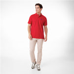 Male model wearing a red polo shirt with a blue embroidered dog logo and tan pants, standing front view