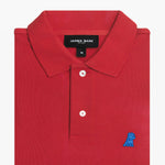 Folded red polo shirt, showing collar, buttons, brand tag, and blue embroidered dog logo on the chest