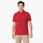 Male model wearing a red polo shirt with a red embroidered dog logo and tan pants, standing front view