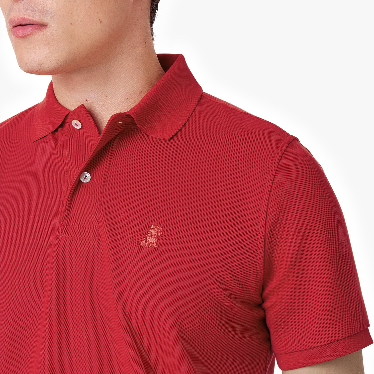 Close-up of a red polo shirt showing the collar, buttons, brand tag, and red embroidered dog logo