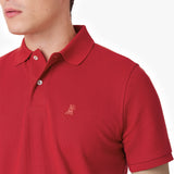 Close-up of a red polo shirt showing the collar, buttons, brand tag, and red embroidered dog logo