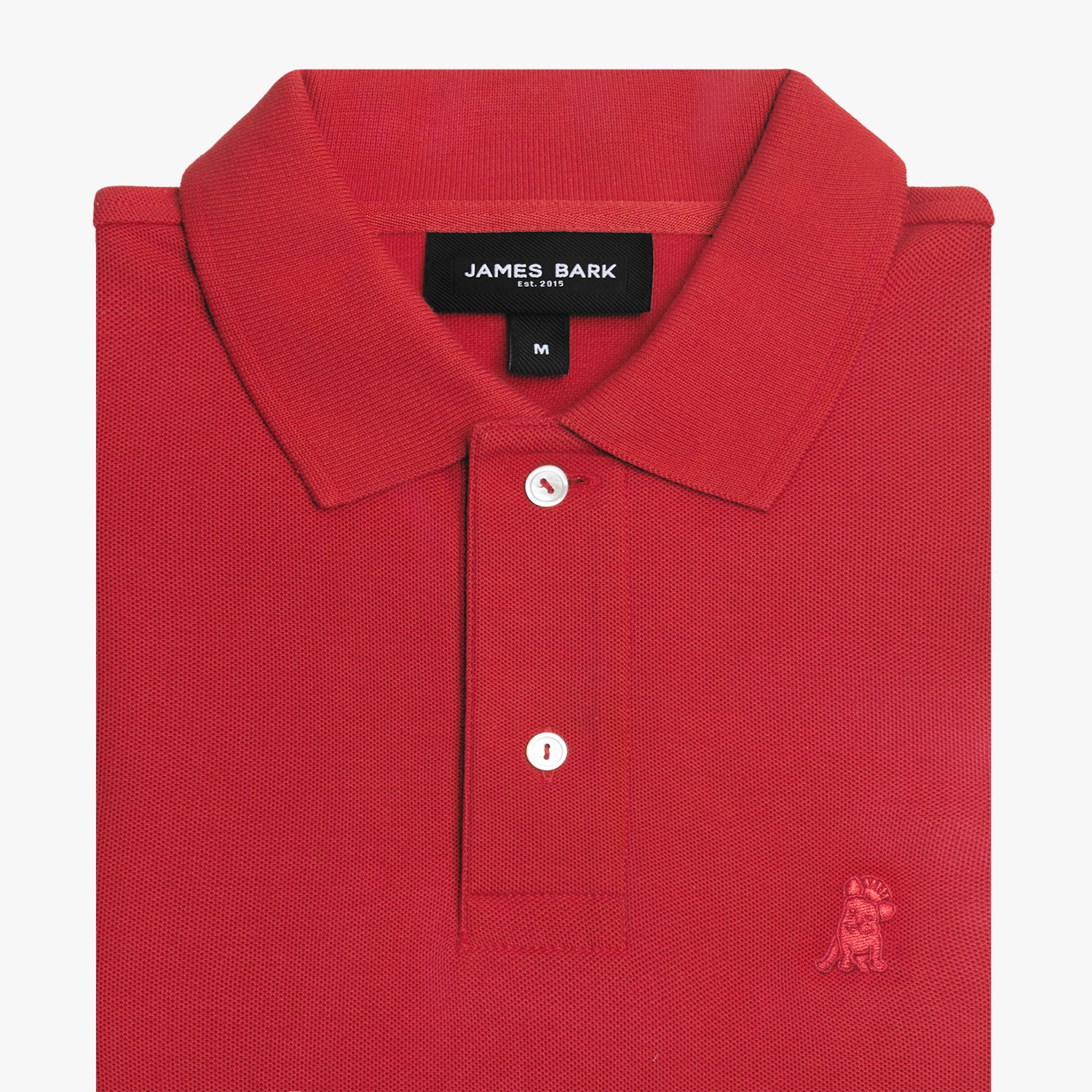 Folded red polo shirt showing collar, buttons, brand tag, and red embroidered dog logo on the chest