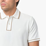 Close-up of a male model wearing a white short-sleeve polo shirt with beige contrast details on the collar, button placket, and sleeve cuffs. The polo features a two-button design and a subtle embroidered dog logo on the chest