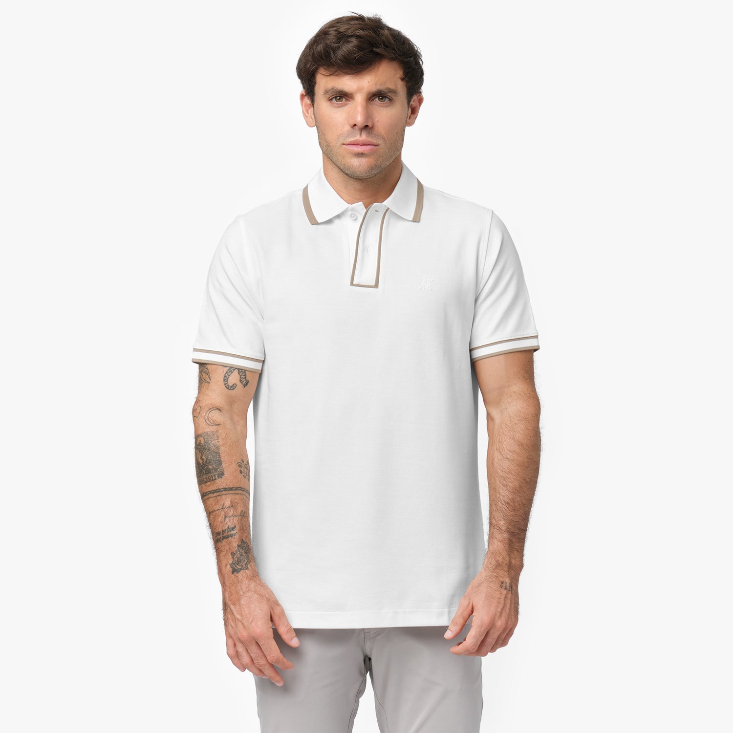 Male model wearing a white short-sleeve polo shirt with beige contrast details on the collar and sleeve cuffs. The polo features a buttoned placket and a subtle embroidered logo on the chest. Paired with light gray trousers for a clean, sophisticated look