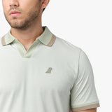 A close-up of a man wearing a light-colored, striped polo shirt with a contrasting collar and sleeve edges. The collar is open, and a small embroidered logo of a dog is visible on the left side of the chest. The fabric appears soft, and the background is plain white