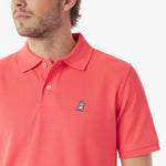 Close-up of a man wearing a red polo shirt with a small logo on a white background