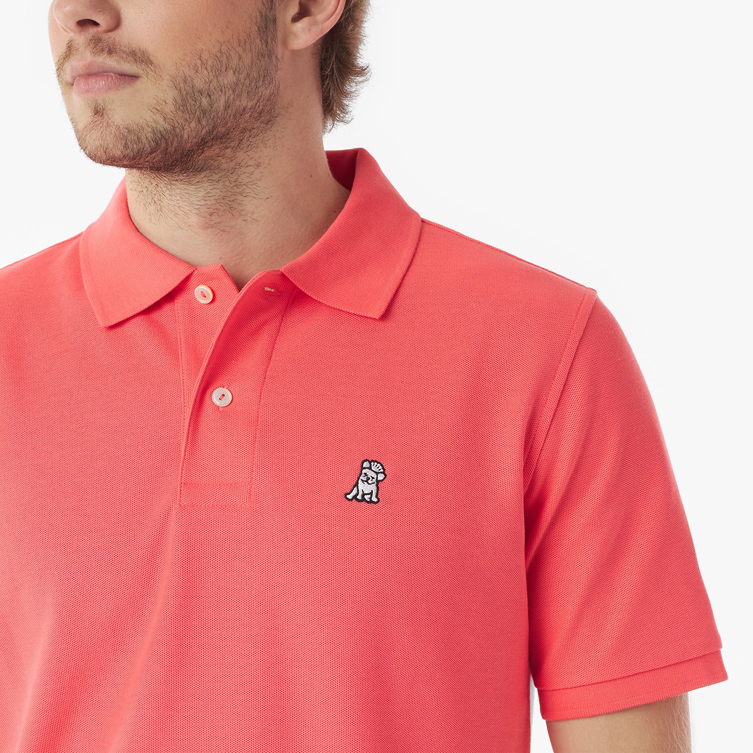 Close-up of a man wearing a red polo shirt with a small logo on a white background