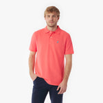 Man wearing a coral polo shirt with a small logo on a white background