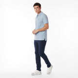 Full body picture of a man wearing a light blue polo shirt and navy pants on a white background