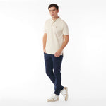 Full body picture of a man wearing a beige polo shirt and navy pants on a white background
