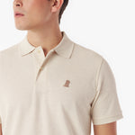 Close-up of a beige polo shirt with a small logo on a white background