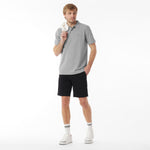 Man wearing a gray polo shirt and black shorts on a white background