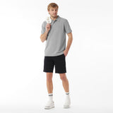 Man wearing a gray polo shirt and black shorts on a white background