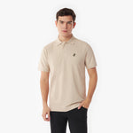 Man wearing a beige polo shirt with a small logo on a white background