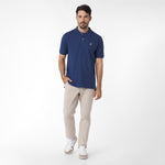 Man wearing a blue polo shirt and beige pants on a white background