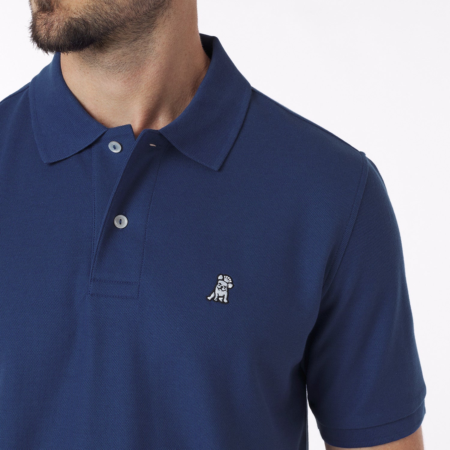 Close-up of a navy blue polo shirt with a small logo on a white background